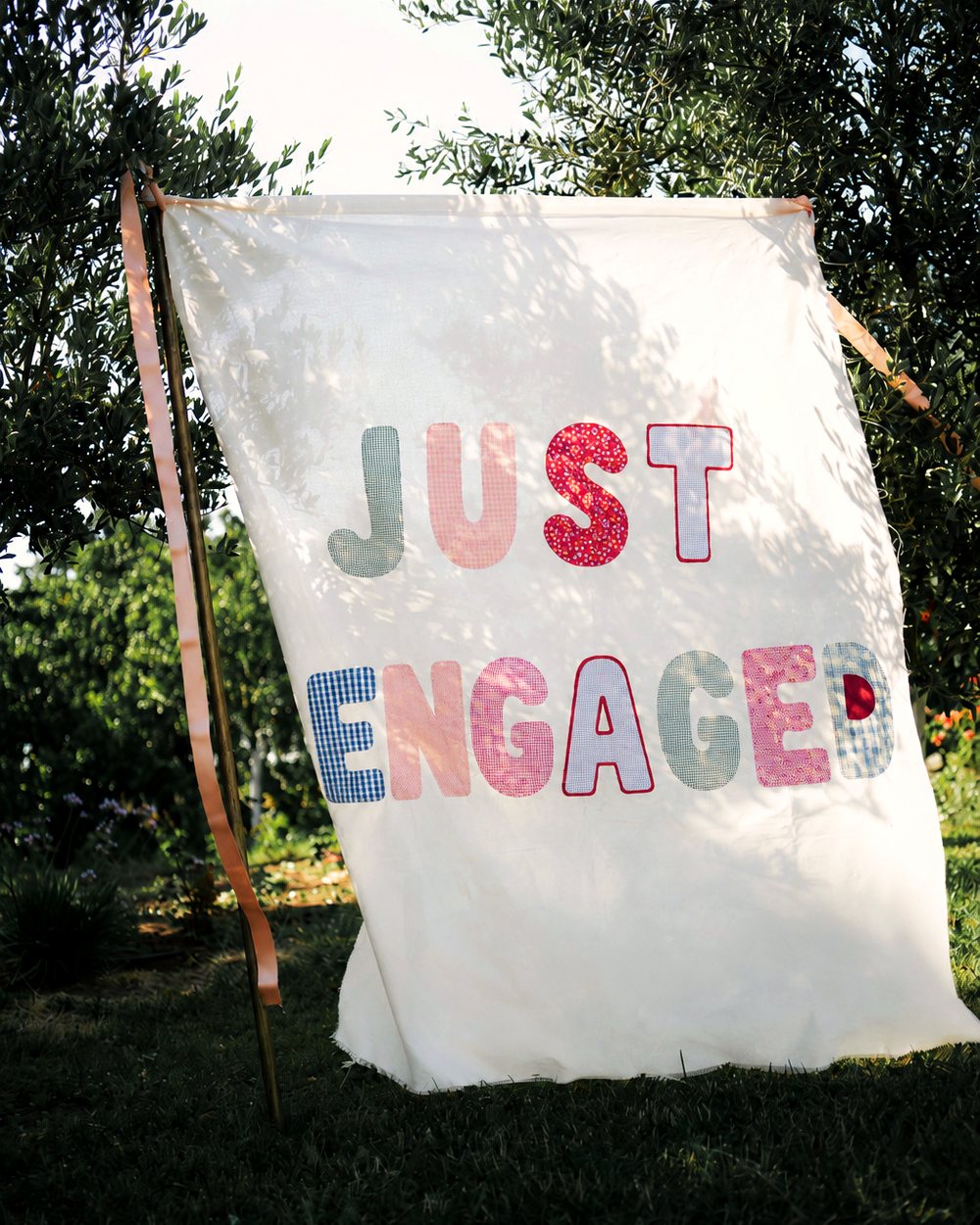 Benekli ışıkta dikey asılmış JUST ENGAGED bannerı